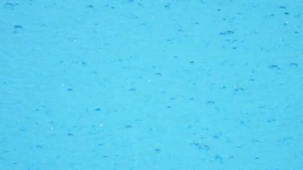 Gotas de chuva caem na água azul da piscina. close-up. 4k, câmera lenta — Vídeo de Stock