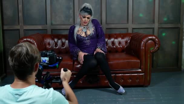 Travesti taklitleri kavramı. yakışıklı genç kadın kıyafetlerini giymiş. profesyonel travestian sanatçı, bir operatör bir fotoğraf Studio için poz veriyor. klip çekim. 4k. — Stok video