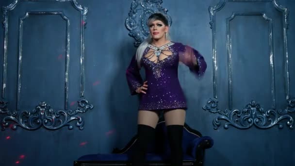 O conceito de paródias travestis. jovem bonito vestido com roupas de mulher. um artista profissional travestiano, posa em um estúdio de fotografia. Tiro no clip. 4k . — Vídeo de Stock