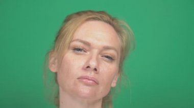 Sevimli sarışın genç kadın. yeşil bir arka plan üzerinde. duygular gösterir. o bir şey incelemektedir. odağı değiştirmelisiniz. Yavaş hareket, yakın çekim