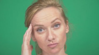 Genç ve güzel sarışın bir kadın. yeşil bir arka plan üzerinde. duygular gösterir. bir şey düşünecek. ve fikir belirtisi gösterir. Ağır çekim, yakın