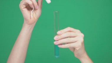 yakın çekim, eller tampon gücü kontrol etmek için mavi sıvı ile tüp bebek bez koyun. yeşil bir arka plan üzerinde. 4k, ağır çekim