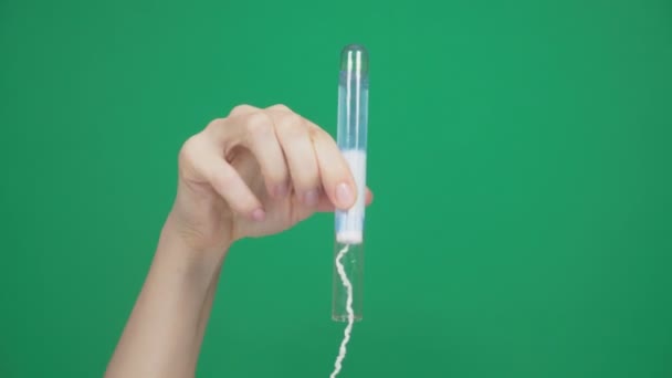 클로즈업, 여성 손에 파란색 액체는 탐폰의 강도 확인 하는 테스트 튜브에 면봉을 배치 합니다. 에 녹색 배경. 4 k, 슬로우 모션 — 비디오