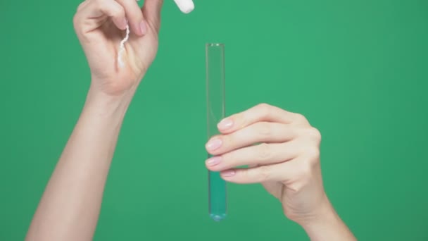 クローズ アップ、女性の手は、タンポンの強度を確認する、ブルー液で試験管に綿棒を配置します。緑の背景。4 k、スローモーション — ストック動画