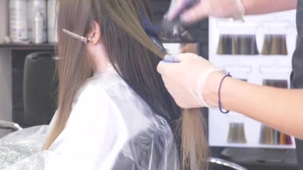 Gros plan, coiffeur professionnel. processus de peinture des cheveux d'une fille brune avec un tonique tonifiant pour les cheveux. Couleur bleue . — Video