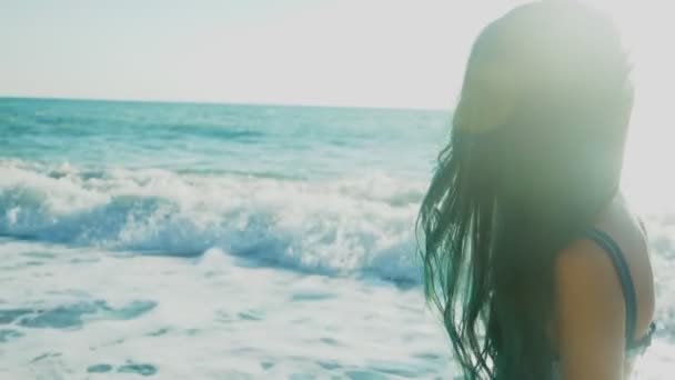 Belle fille brune aux longs cheveux bleus, se développant dans le vent, sur fond de vagues de mer lors d'une tempête. liberté, créativité, mystère. 4k, au ralenti — Video