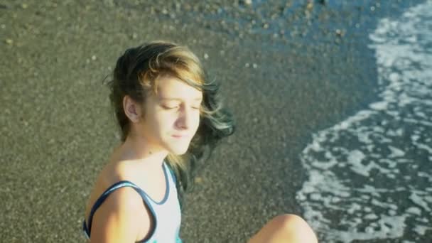 Hermosa chica morena con el pelo largo y azul que se desarrolla en el viento, sobre un fondo de una playa de arena. libertad, creatividad, misterio. 4k, cámara lenta — Vídeos de Stock