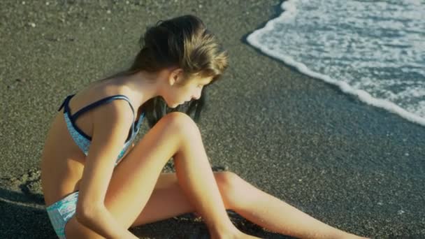 Belle fille brune aux longs cheveux bleus se développant dans le vent, sur fond de plage de sable fin. liberté, créativité, mystère. 4k, au ralenti — Video