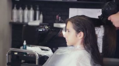 yakın çekim, profesyonel kuaför. saç için tonlama bir tonik esmer bir kızla saç boyama işlemi. saç kurutma makinesi, yavaş hareket ile saç kurutma