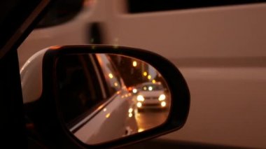 Gece sürüş. Arabayı görünümünden gece şehirde sürüş sırasında yan dikiz ayna üzerinde. şehir ışıkları bulanık. 4k
