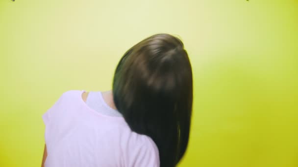 Het concept van haar verven, toning, kleuren haar. Gelukkig blijkt het meisje op een gele achtergrond, haar lange haren, geschilderd in blauw. 4k, slow-motion. — Stockvideo