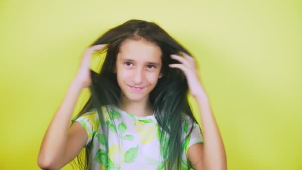 El concepto de teñir el cabello, tonificar, colorear el cabello. la chica sobre un fondo amarillo, felizmente demuestra su pelo largo, pintado de azul. 4k, cámara lenta . — Vídeo de stock