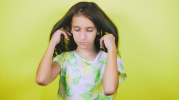 Le concept de teinture des cheveux, tonifiant, coloration des cheveux. la fille sur un fond jaune, montre heureusement ses cheveux longs, peints en bleu. 4k, au ralenti . — Video