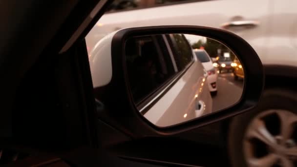 Conduciendo de noche. La vista desde el coche en el espejo retrovisor lateral mientras conduce a través de la ciudad nocturna. luces borrosas de la ciudad. 4k — Vídeos de Stock