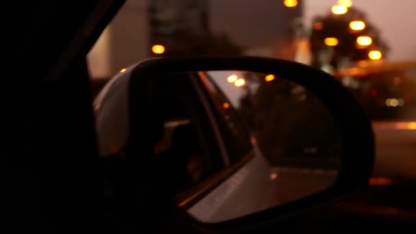 Водіння вночі. Вид з автомобіля на дзеркало заднього виду під час руху по нічному місту. розмиті міські вогні. 4k — стокове відео