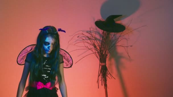 ハロウィーン ポーズと赤い背景の上で踊って 魔女に扮した半分の顔でメイク骨格を持つ少女 スローモーション — ストック動画