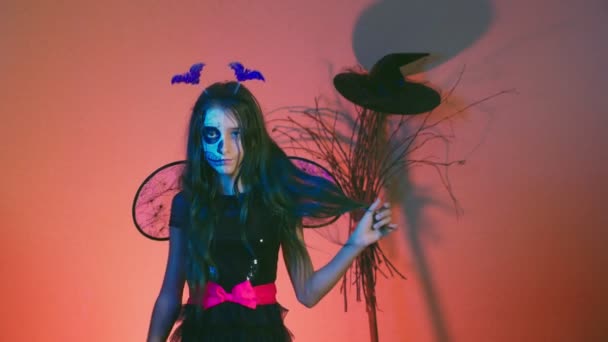 Halloween dívka s make-up kostra na polovinu tváří, oblečený jako čarodějnice, pózování a tančí na červeném pozadí. 4k, pomalý pohyb — Stock video