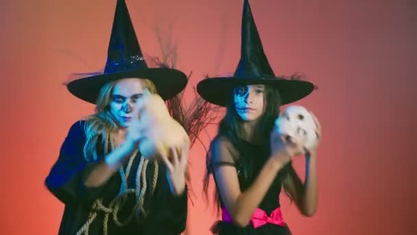 Halloween, Dziewczyna z makijażem, szkielet pół twarzy i jej matka, ubrany jak czarownice, pozowanie i taniec na czerwonym tle. 4k, zwolnionym tempie — Wideo stockowe