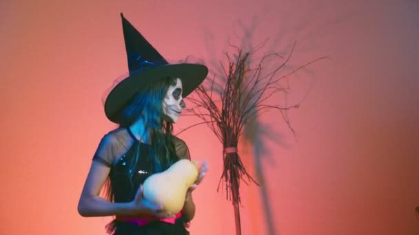 Halloween, flicka med smink skelett halva ansiktet, klädd som en häxa, poserar och dansar på en röd bakgrund. 4k, Slowmotion — Stockvideo