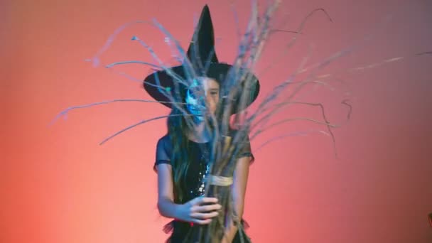 Halloween, meisje met make-up skelet op halve gezicht, verkleed als een heks, die zich voordeed en dansen op een rode achtergrond. 4k, slow-motion — Stockvideo