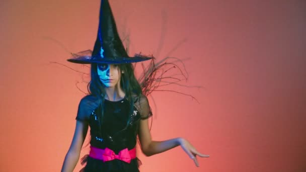 Halloween, girl with makeup skeleton on half face, dressed as a witch, posing and dancing on a red background. 4k, slow motion — Stock Video