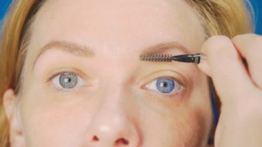 Süper yakın çekim, kadın kaş kalemi kaşları için boyar. 4k, ağır çekim. kadının ona makyaj yapması