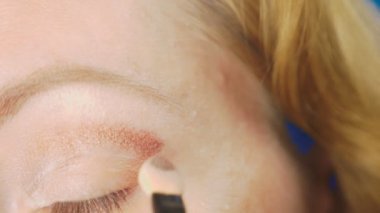 Süper yakın çekim, bir kadının onu göz makyaj yapması göz kapağı gölgeler ile boyar. 4k, ağır çekim