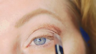 Süper yakın çekim, bir kadının onu göz makyaj yapması göz kapağı gölgeler ile boyar. 4k, ağır çekim