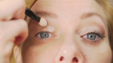 Süper yakın çekim, bir kadının onu göz makyaj yapması göz kapağı gölgeler ile boyar. 4k, ağır çekim