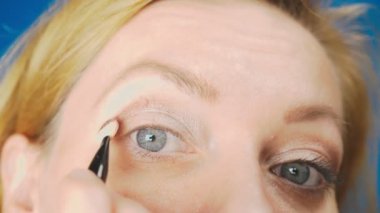 Süper yakın çekim, bir kadının onu göz makyaj yapması göz kapağı gölgeler ile boyar. 4k, ağır çekim