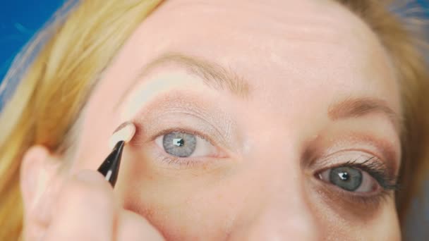 Супер крупним планом, жінка, яка робить макіяж очей, фарбує повіку тінями. 4k, повільний рух — стокове відео