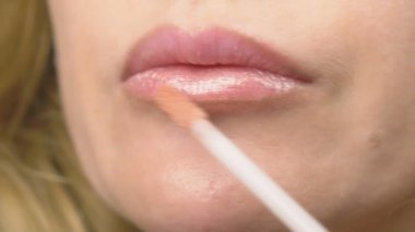 Süper yakın çekim, yavaş hareket, 4k. bir kadının dudakları ile dudak parlatıcısı boyuyor. Dudak makyaj, dermatolojik hastalık dudaklar cilt üzerinde. Tilki tilki granül