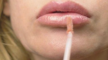 Süper yakın çekim, yavaş hareket, 4k. bir kadının dudakları ile dudak parlatıcısı boyuyor. Dudak makyaj, dermatolojik hastalık dudaklar cilt üzerinde. Tilki tilki granül