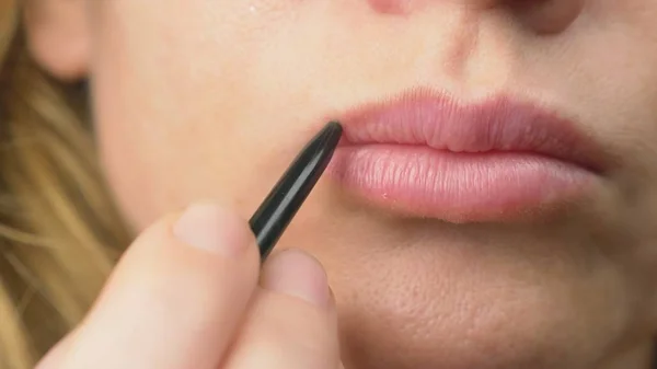 Super close-up, uma mulher pinta os lábios com um lápis para os lábios. maquiagem labial, doença dermatológica na pele dos lábios. Grânulos de raposa — Fotografia de Stock