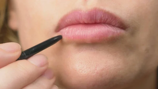 super close-up, a woman paints her lips with a pencil for her lips. lip makeup, dermatological disease on the skin of the lips. Fox Foxes granules