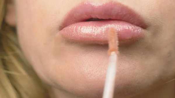 Super-Nahaufnahme. Eine Frau bemalt Lippen mit Lipgloss. Lippen-Make-up, Hauterkrankungen auf der Haut der Lippen. Füchse-Granulat — Stockfoto