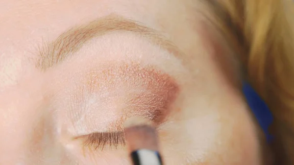 Super close-up, een vrouw doet haar oog make-up, schildert het ooglid met schaduwen. — Stockfoto