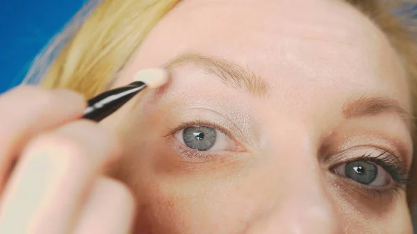 Super close-up, uma mulher fazendo sua maquiagem olho, pinta a pálpebra com sombras . — Fotografia de Stock