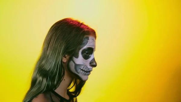 Halloween lány make-up csontváz fél arc, öltözött boszorkány, pózol a élénksárga a háttér. közeli kép: — Stock Fotó