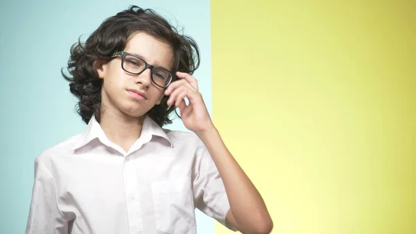 Portretten van een tiener in schooluniform en glazen op een gekleurde achtergrond. concept van leren. De tiener maakt grappige gezichten. hij wanhopig omdat hij niet wil om naar school te gaan. kopie ruimte — Stockfoto