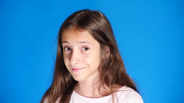 Aranyos lány tinédzser néz a kamera nevetve, és tesz egy vicces arc kifejezése. közelről. színes háttérrel — Stock Fotó