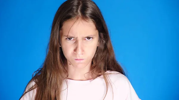 Nahaufnahme. gut aussehende schmollende Mädchen schmollt Lippen, auf blauem Hintergrund. beleidigtes Teenie-Mädchen — Stockfoto