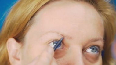 Süper yakın çekim, kadın kaş kalemi kaşları için boyar. 4k, ağır çekim. kadının ona makyaj yapması