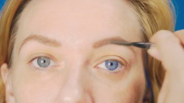 Süper yakın çekim, kadın kaş kalemi kaşları için boyar. 4k, ağır çekim. kadının ona makyaj yapması