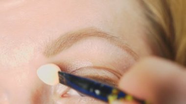 Süper yakın çekim, bir kadının onu göz makyaj yapması göz kapağı gölgeler ile boyar. 4k, ağır çekim
