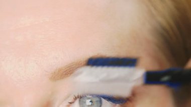 Süper yakın çekim, kadın kaş kalemi kaşları için boyar. 4k, ağır çekim. kadının ona makyaj yapması