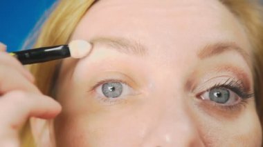 Süper yakın çekim, bir kadının onu göz makyaj yapması göz kapağı gölgeler ile boyar. 4k, ağır çekim