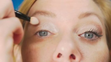 Süper yakın çekim, bir kadının onu göz makyaj yapması göz kapağı gölgeler ile boyar. 4k, ağır çekim