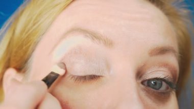 Süper yakın çekim, bir kadının onu göz makyaj yapması göz kapağı gölgeler ile boyar. 4k, ağır çekim