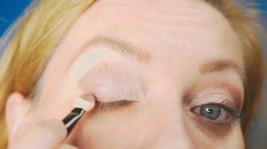 Süper yakın çekim, bir kadının onu göz makyaj yapması göz kapağı gölgeler ile boyar. 4k, ağır çekim